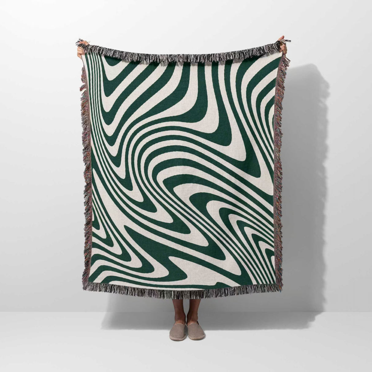 Person holding a large 50x60 forest green modern decorative woven throw blanket against a white background