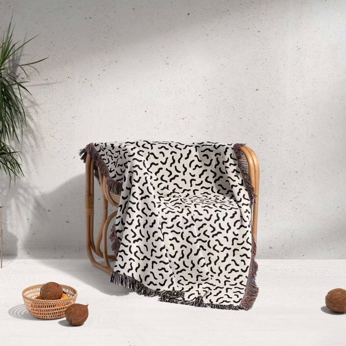 Woven chair with a funky squiggly woven blanket throw tapestry on a light background