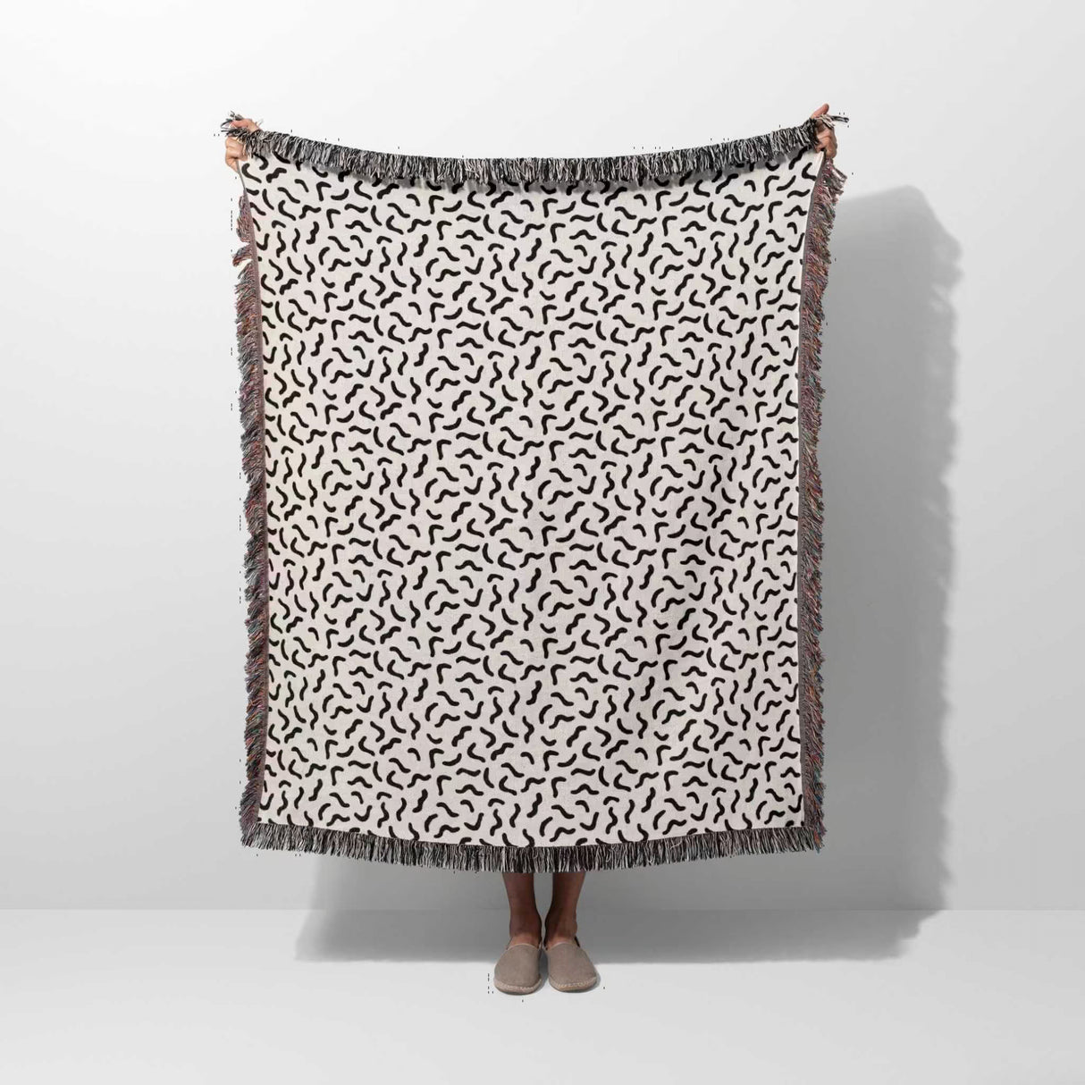 Funky squiggly woven blanket throw tapestry held by a person on a white background
