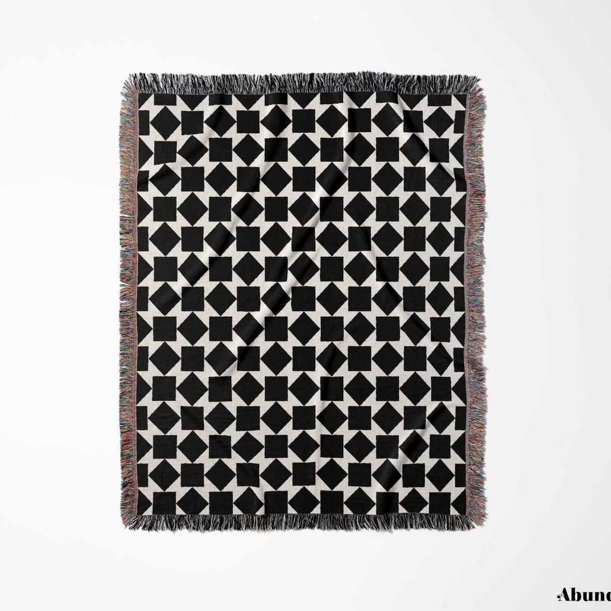 Black and white geometric square patterned woven blanket throw full view with fringe on a light gray background.