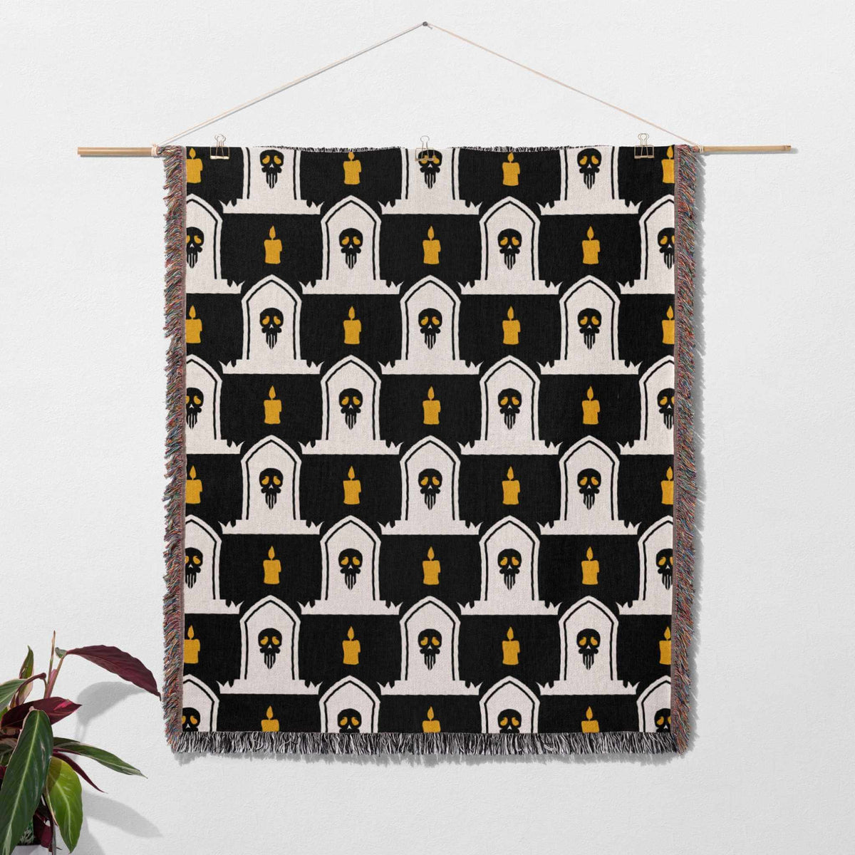Decorative blanket with black, white, and gold pattern hanging on a wall.
