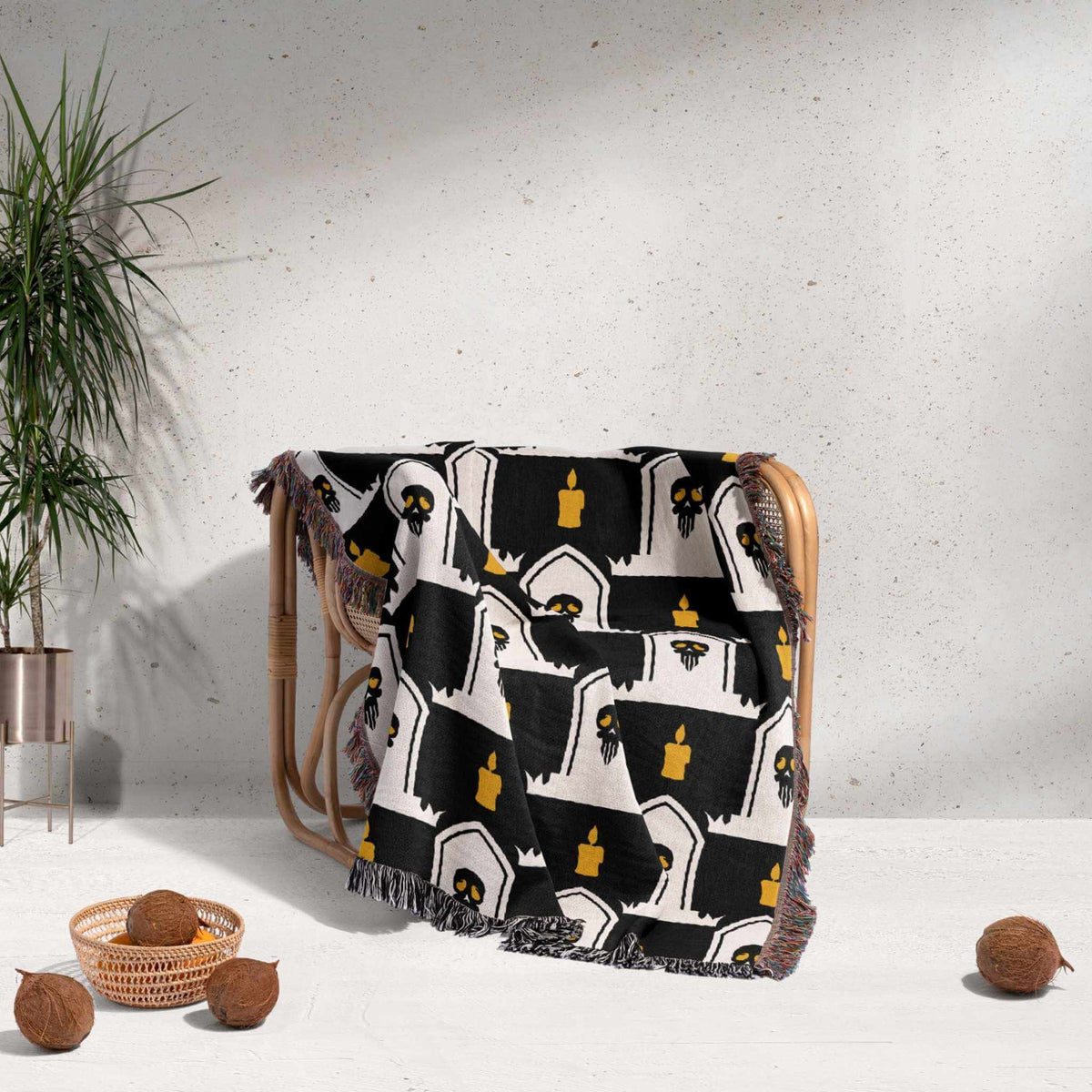 Decorative blanket with black and white pattern draped over a chair against a light gray wall.