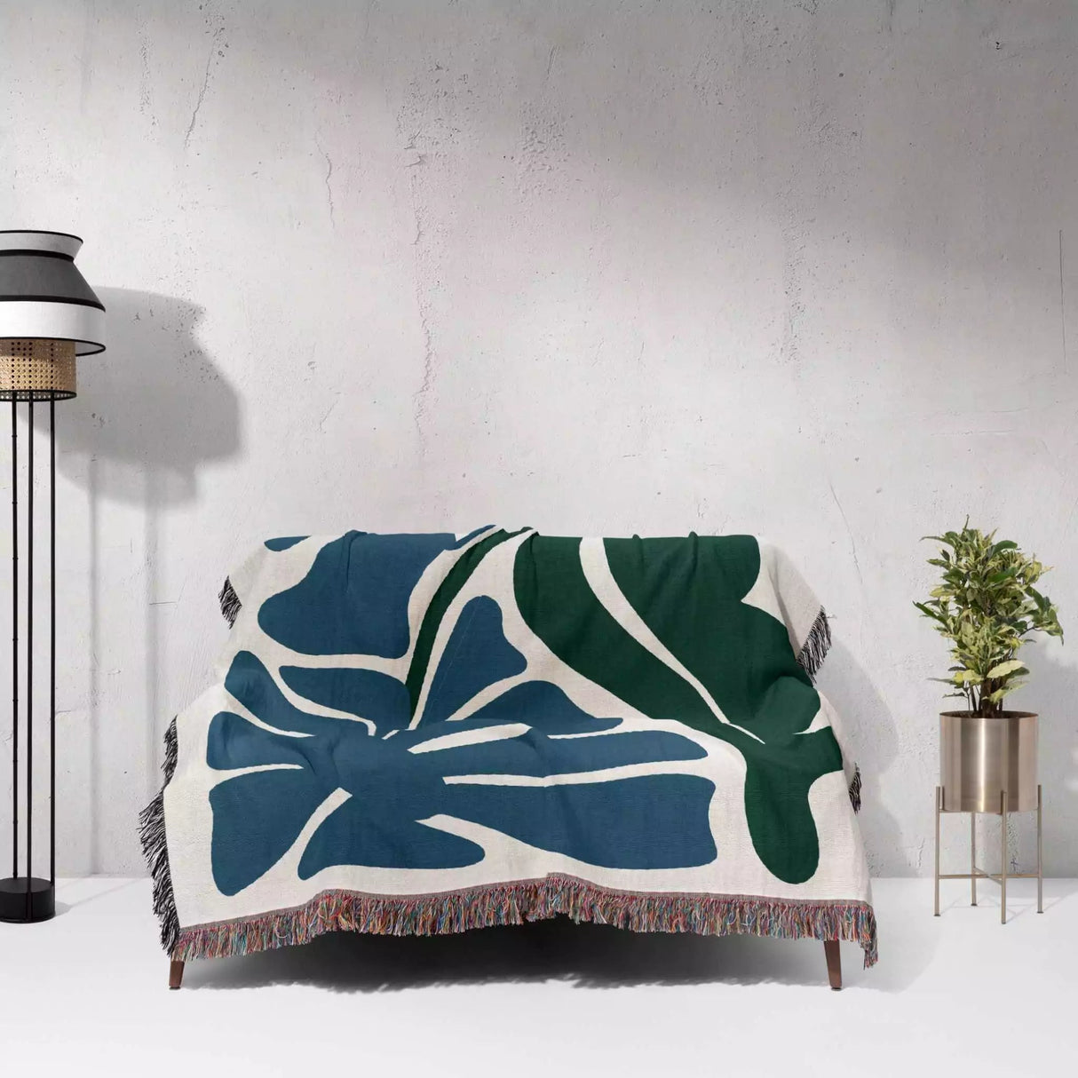 Floral patterned Henri Matisse blue flowers woven throw blanket draped over a chair against a white wall.