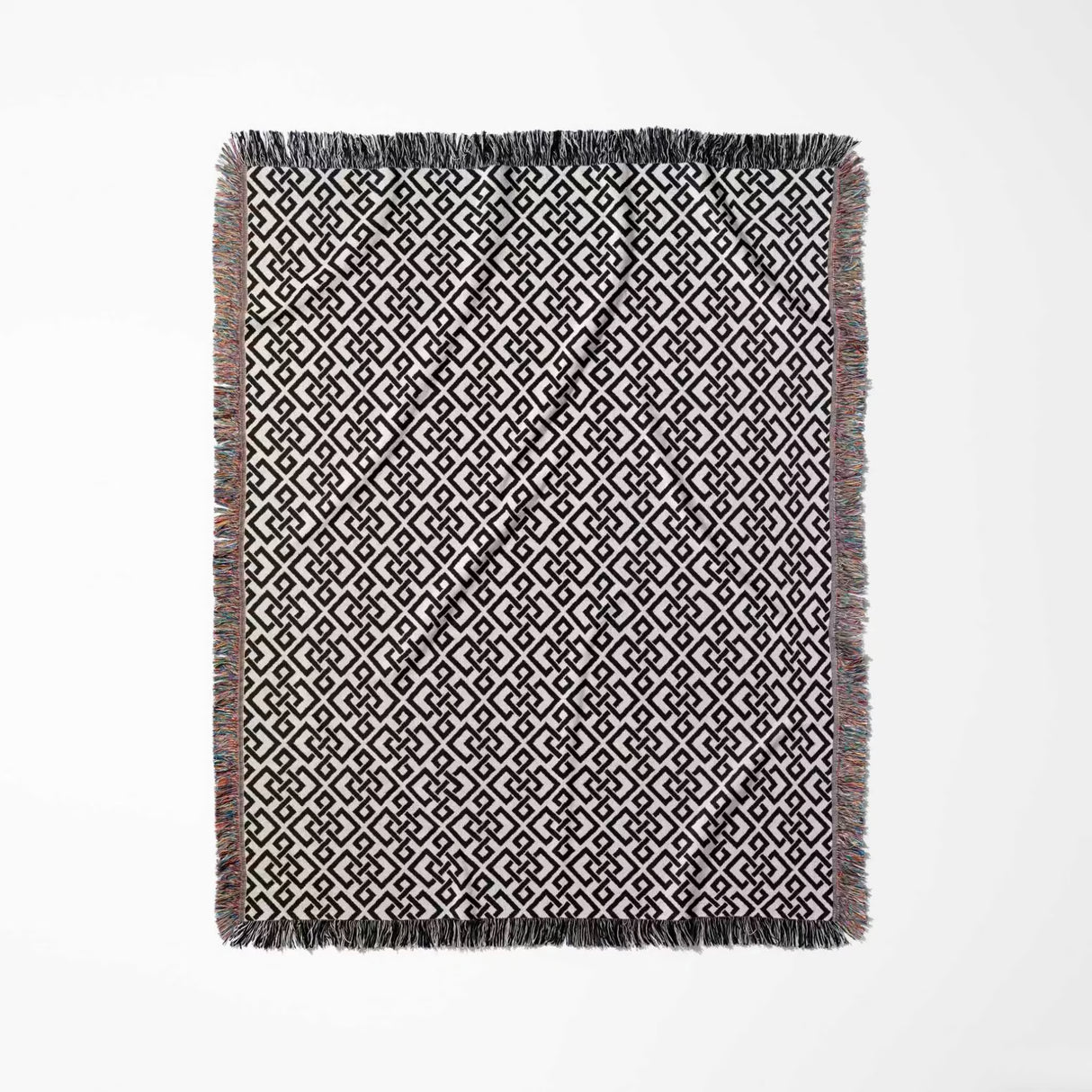 Black and white luxury geometric patterned woven blanket throw tapestry with fringe full view on a white background.