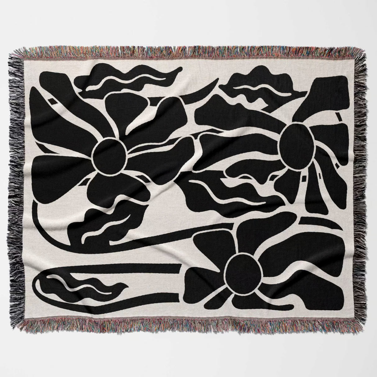 Matisse style black and white botanical cotton woven throw blanket with black floral patterns on a beige background