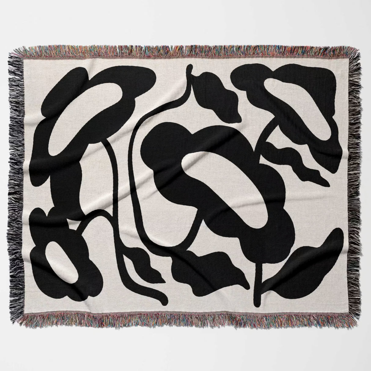 Decorative Matisse style black and white cotton woven throw blanket with black abstract leaf pattern on a beige background