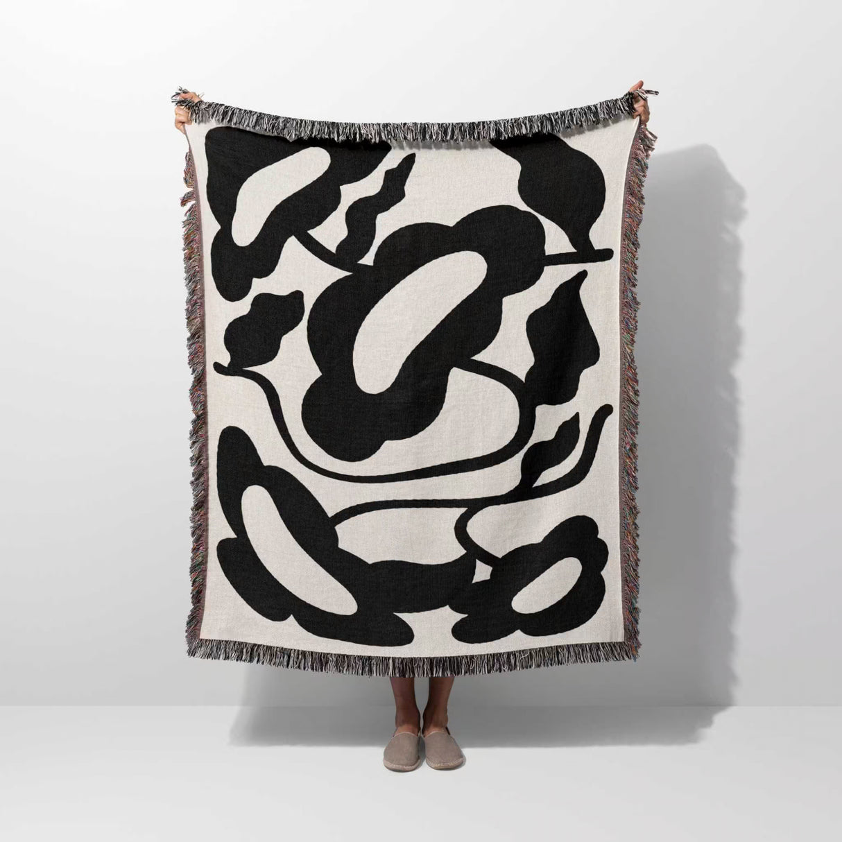 Matisse style black and white cotton woven throw blanket hold by a person on a white background