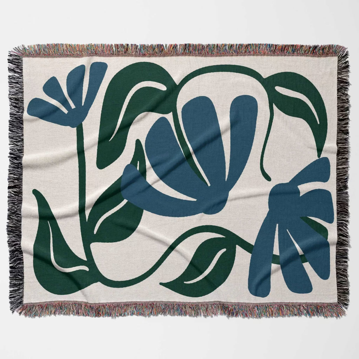 Floral patterned Matisse style blue floral cotton woven throw blanket with blue and green leaves on a beige background