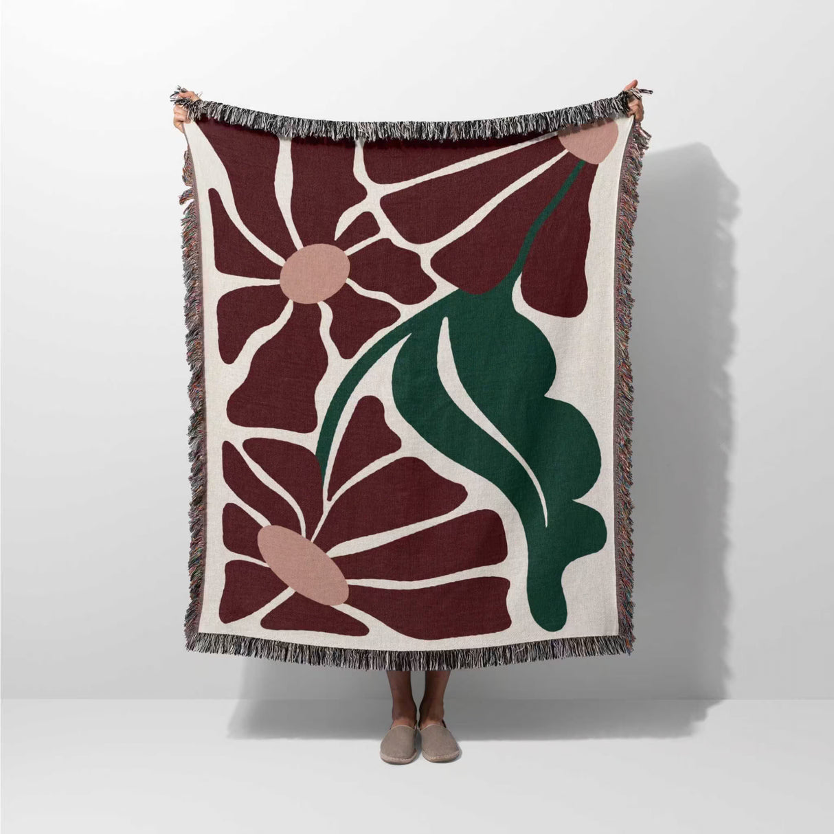 Matisse style botanical cotton woven throw blanket draped over a person on a white background