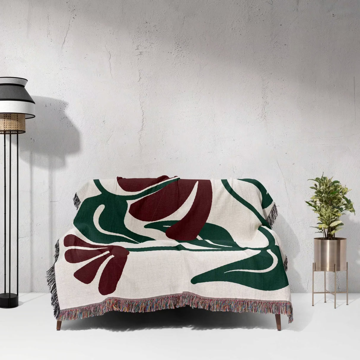 Decorative Matisse style red floral cotton woven throw blanket with a floral pattern draped over a chair against a white wall.