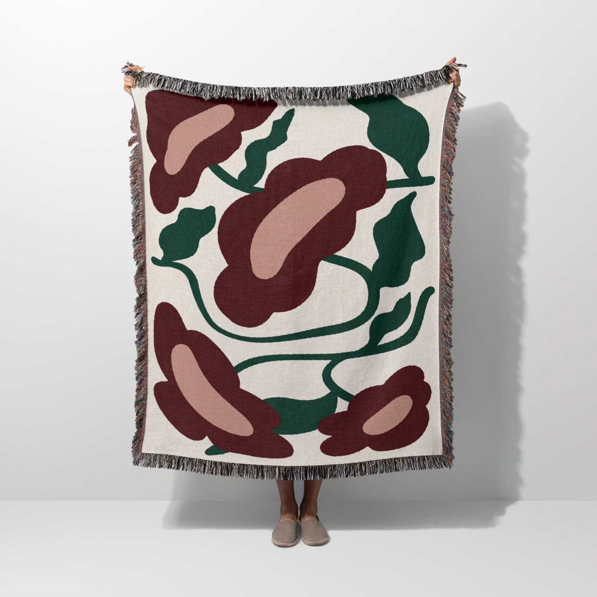 Floral patterned Matisse style red flowers cotton woven throw blanket with red and green design on a white background