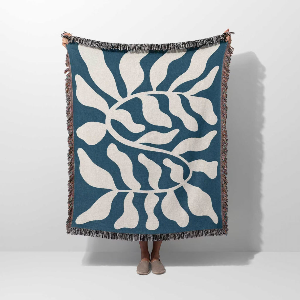 Blue leaf abstract woven Matisse trow blanket tapestry held upright by a person on a white background