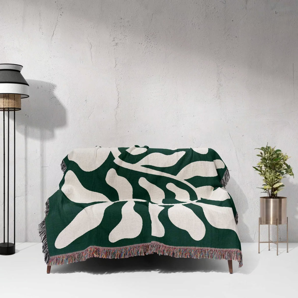 Matisse throw blanket green leaf abstract tapestry draped over a couch against a white wall.
