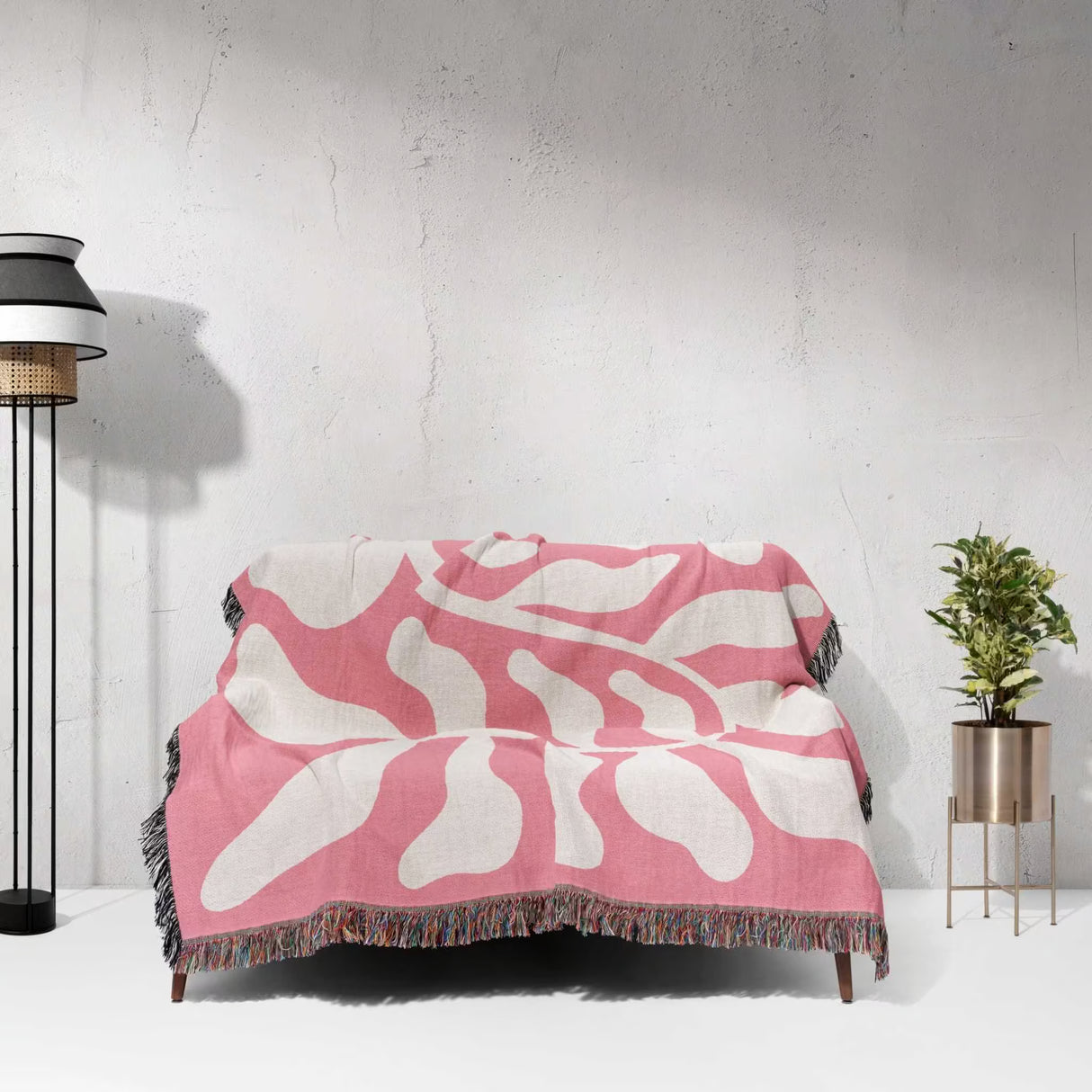 Lighter red abstract Matisse throw blanket draped over a couch against a white wall.