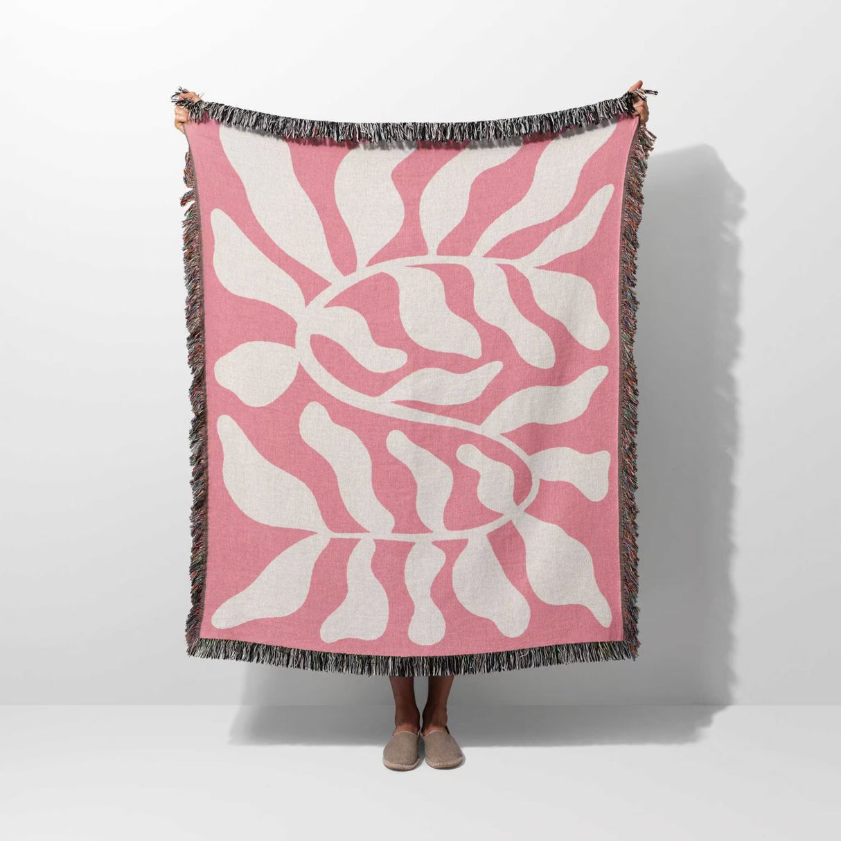 Lighter red abstract Matisse throw blanket held over a person on a white background