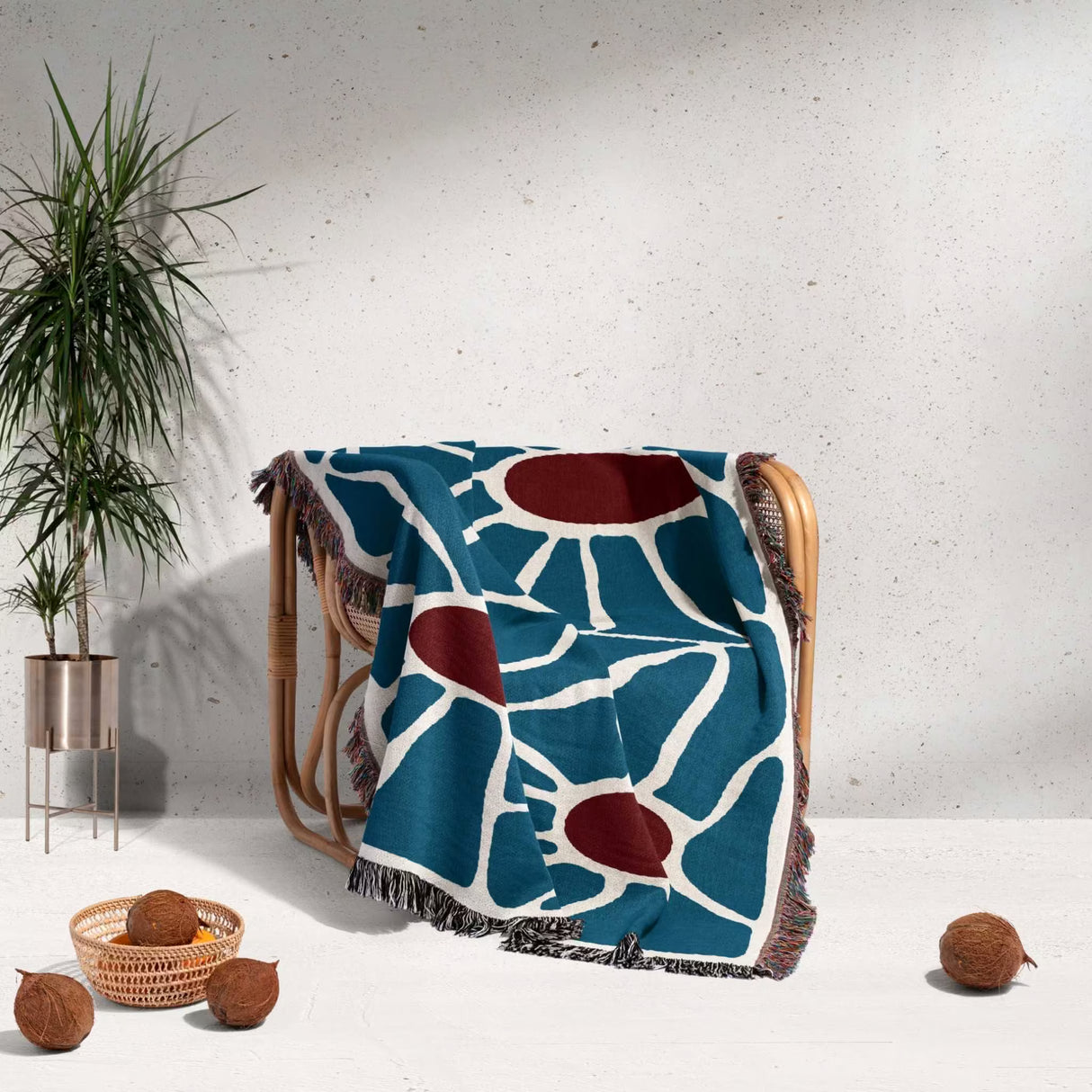 Maximalist Matisse inspired tapestry throw blanket for couch draped over a chair, with a plant and coconuts in the background.