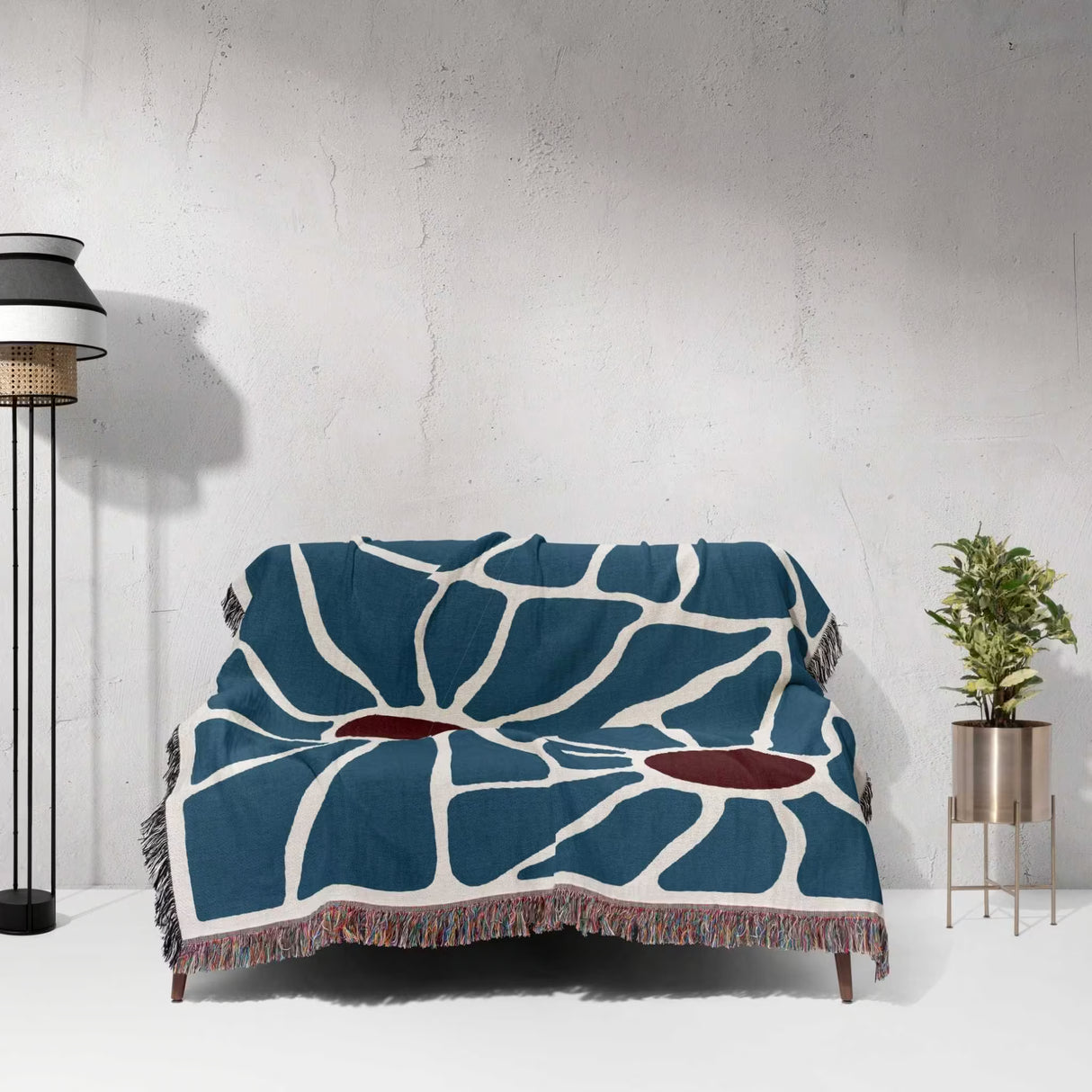 Maximalist Matisse inspired tapestry throw blanket for couch draped over a couch against a white wall.