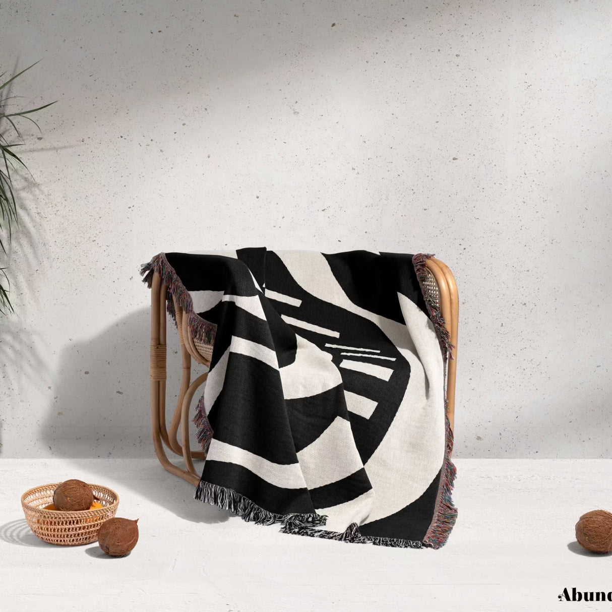 Black and white modern abstract art woven blanket throw tapestry draped over a chair on a light gray background.