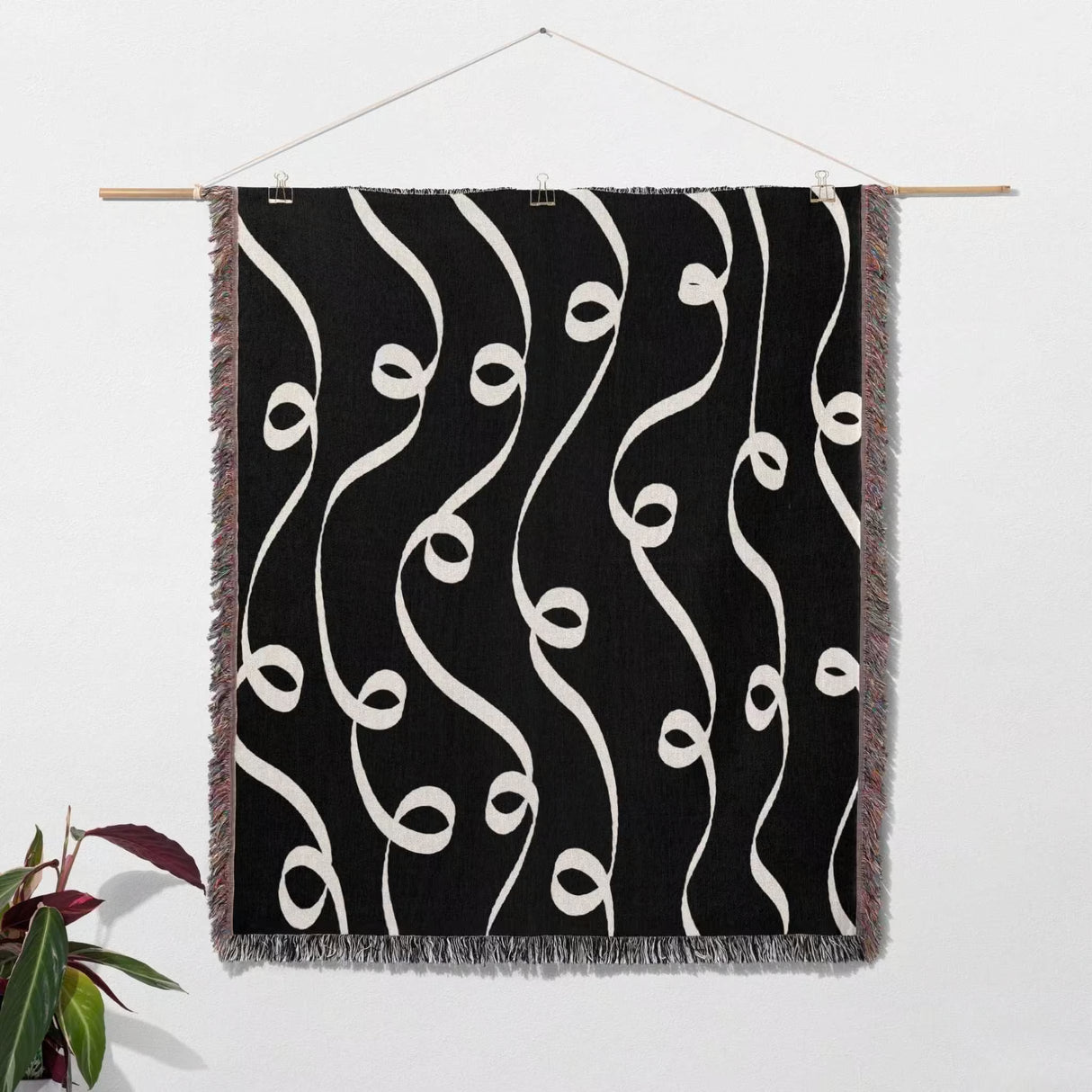 Black and white modern art decorative woven blanket throw tapestry as wall art hanging on a white wall.