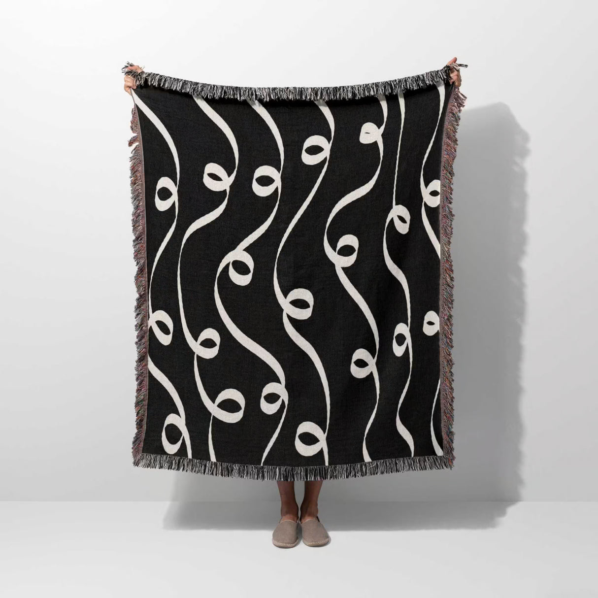 Black and white modern art decorative woven blanket throw tapestry held by a person on a white background