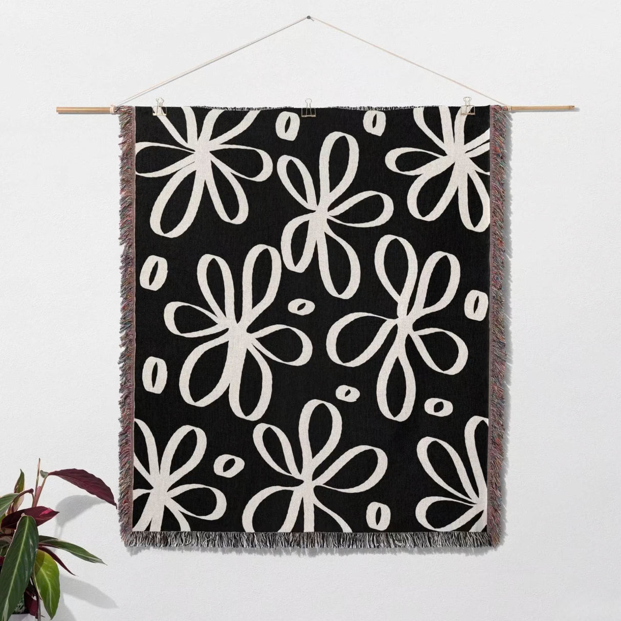 Black and white modern artsy flowers woven blanket throw hanging on a wall as a wall tapestry.