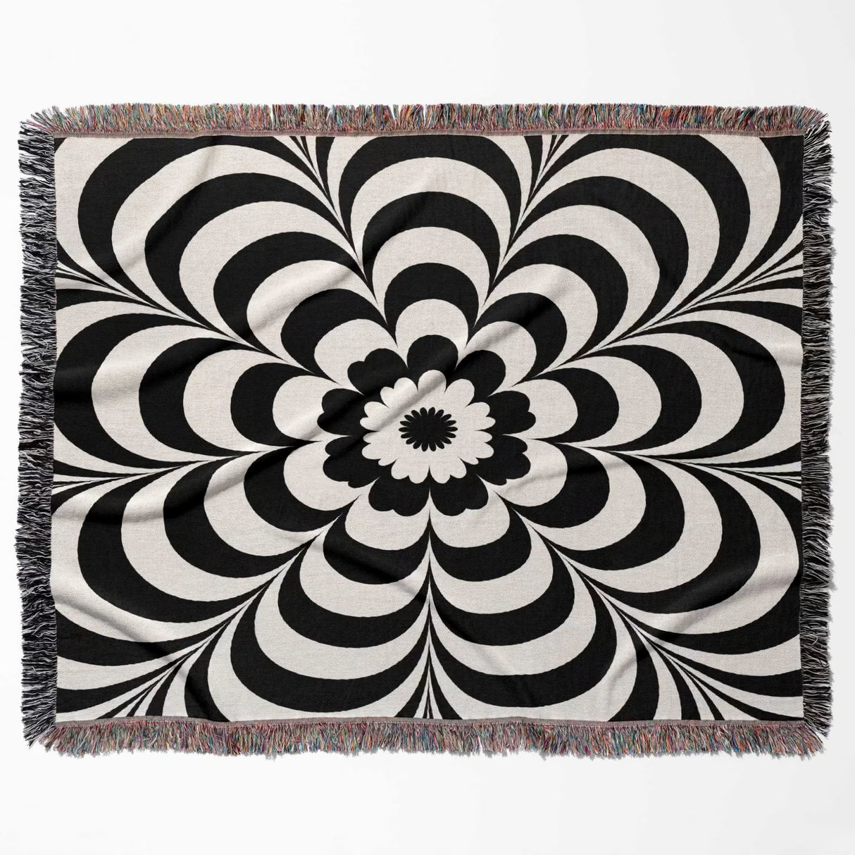Black and white psychedelic flower woven blanket throw tapestry with fringed edges horizontal flat lay on a white background.