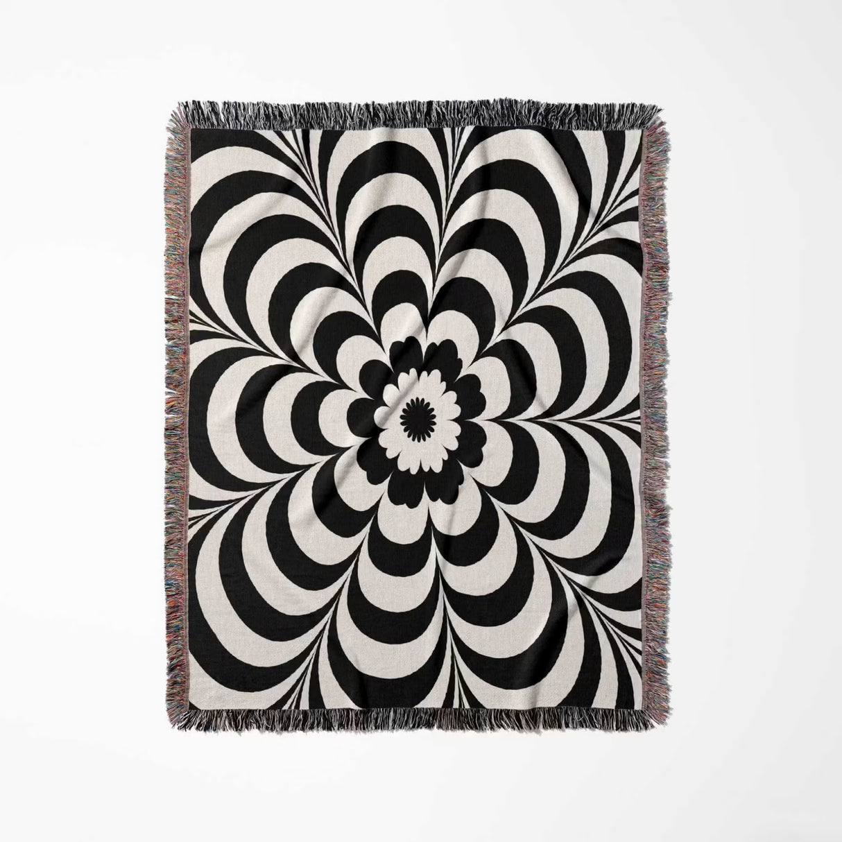 Black and white psychedelic flower woven blanket throw tapestry with fringe vertical full view on a light gray background.