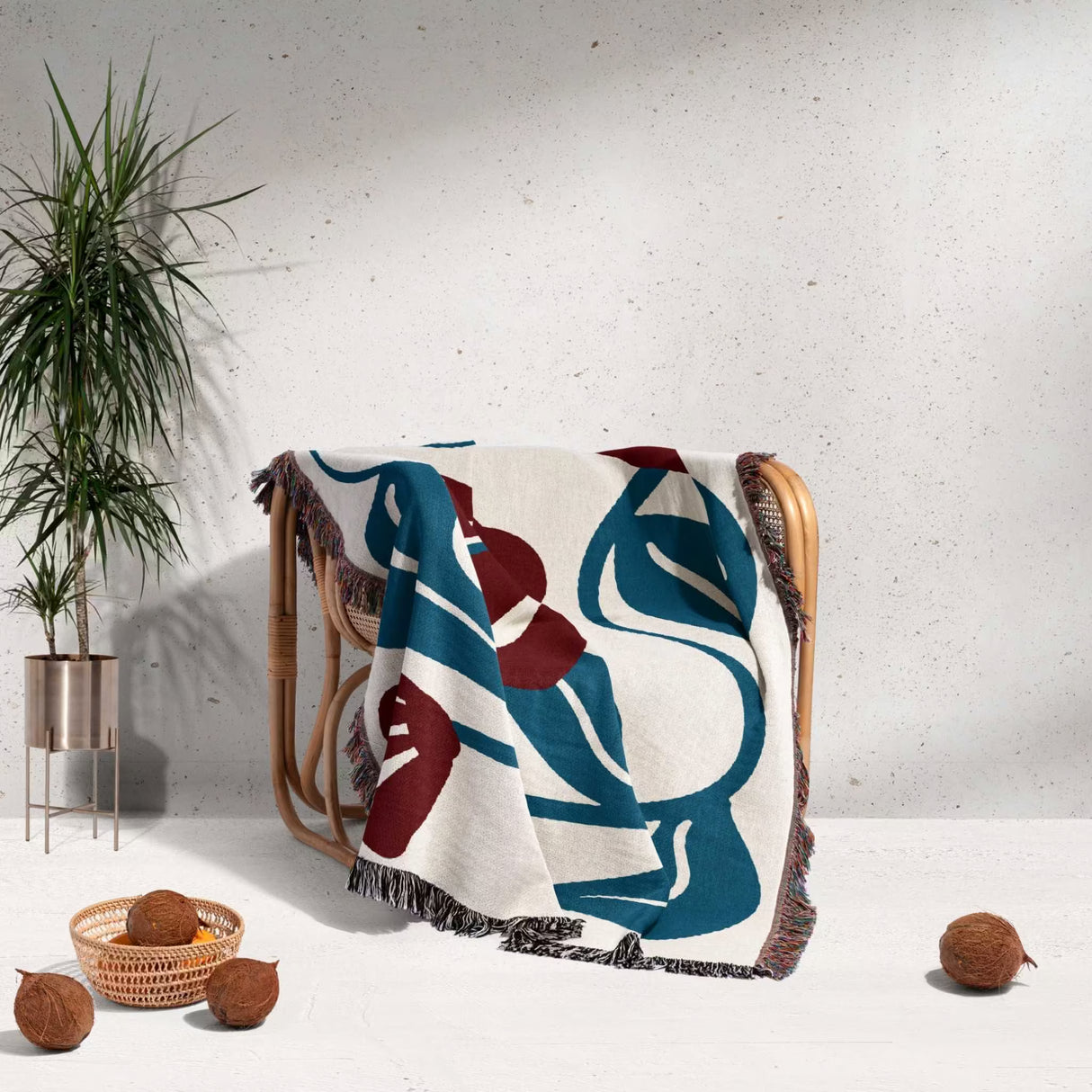 Decorative red and blue Matisse tapestry throw blanket with abstract design draped over a chair against a light gray wall.