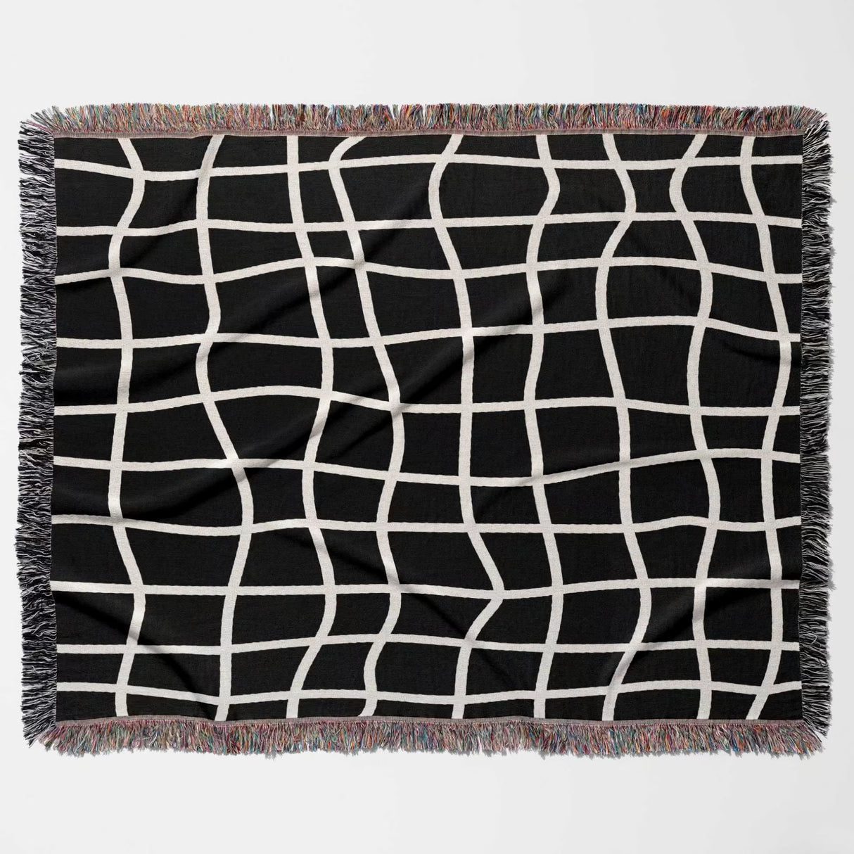 Black and white retro checkered woven blanket throw tapestry with fringe flat lay on a light gray background