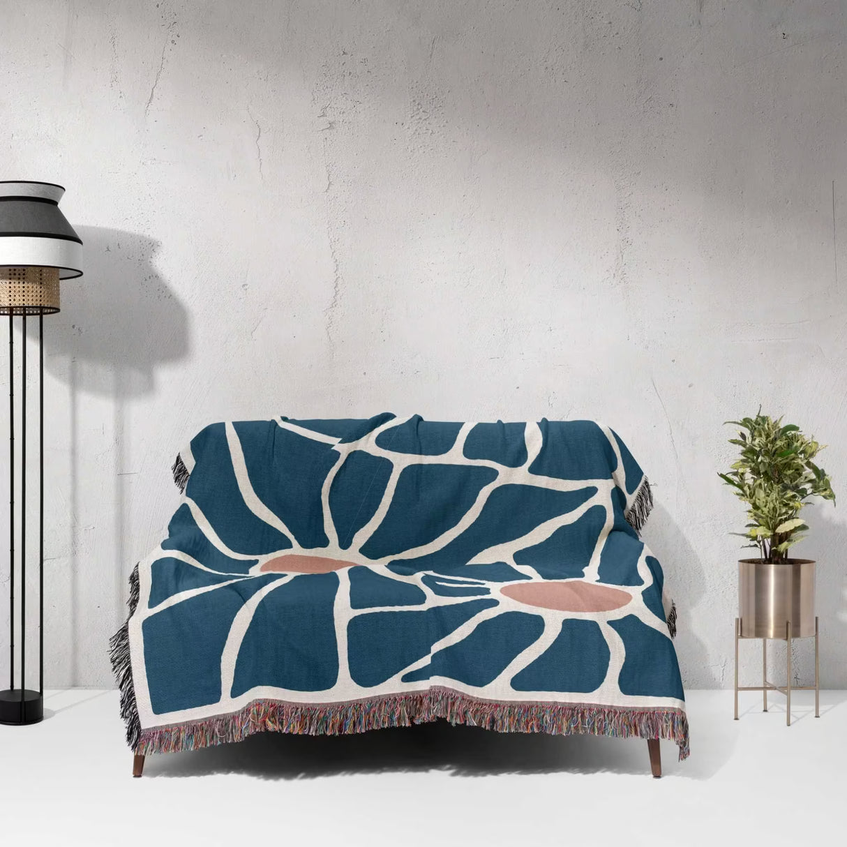 Couch with a retro style Matisse inspired tapestry throw blanket for couch against a white wall.