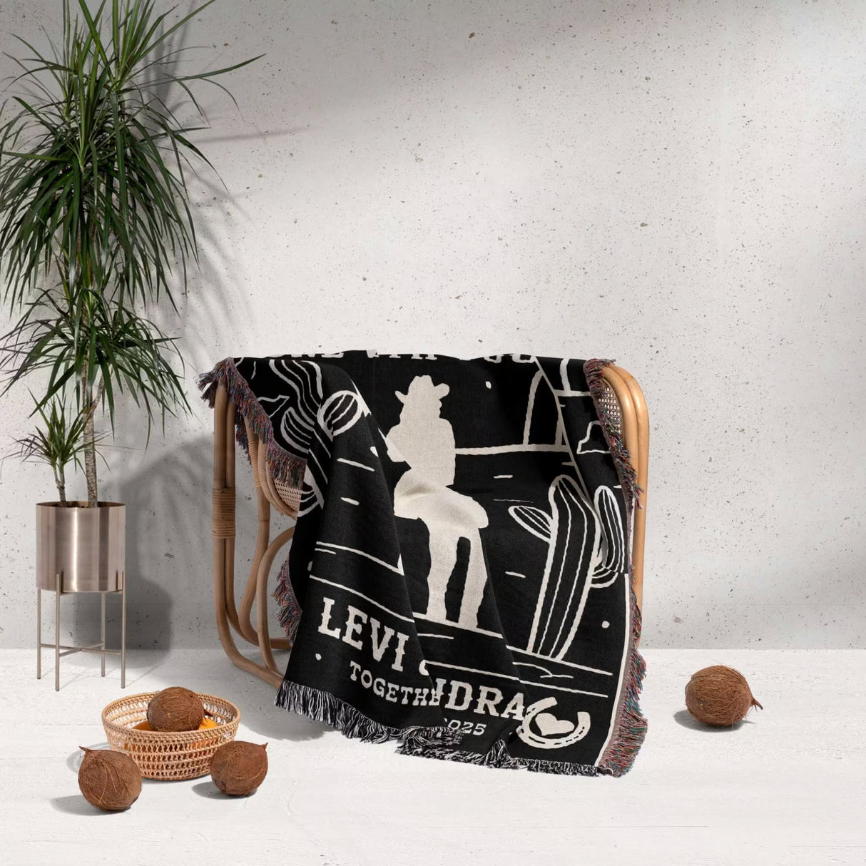 Romantic cowboy and cowgirl 2nd anniversary gift woven throw blanket with white western graphics draped over a chair, with a plant and decor items in the background.
