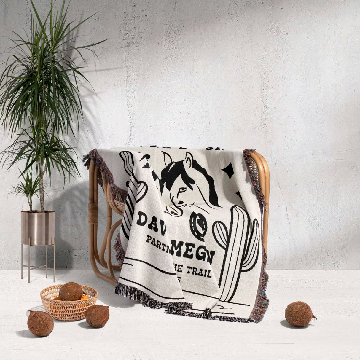 Romantic western cotton anniversary gift - woven throw blanket with graphic design draped over a chair next to a plant and decorative items.