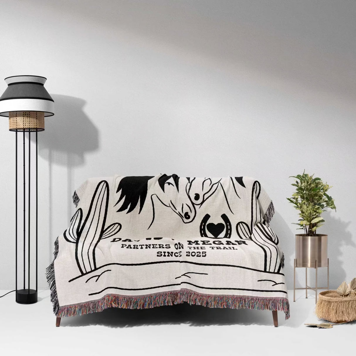 Romantic western cotton anniversary gift - woven throw blanket with horse design and text draped over a couch in a room with a lamp and plant.