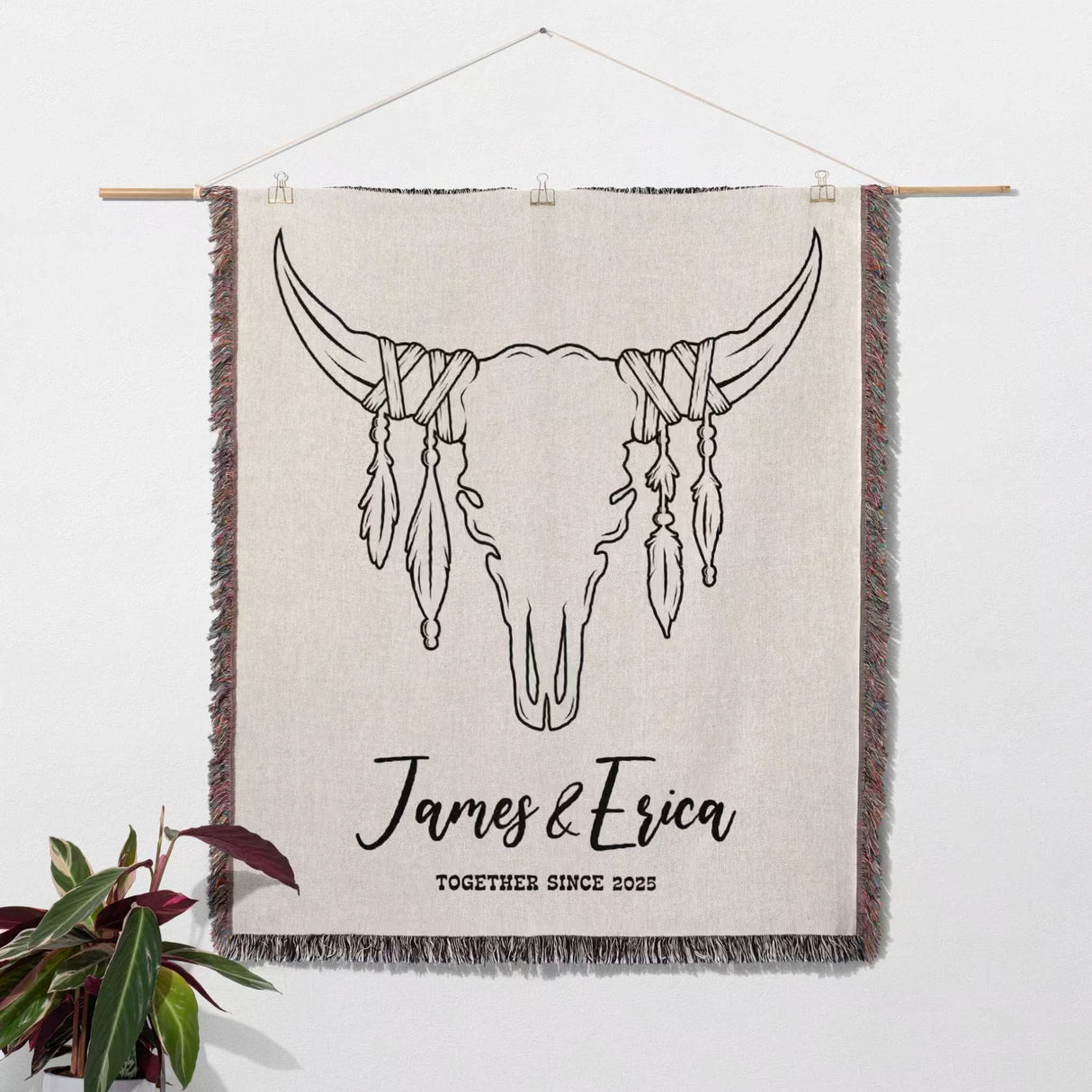 Rustic bull skull cotton anniversary gift woven throw blanket with bull skull design and 'James & Erica Together Since 2022' text, hanging on a white wall.