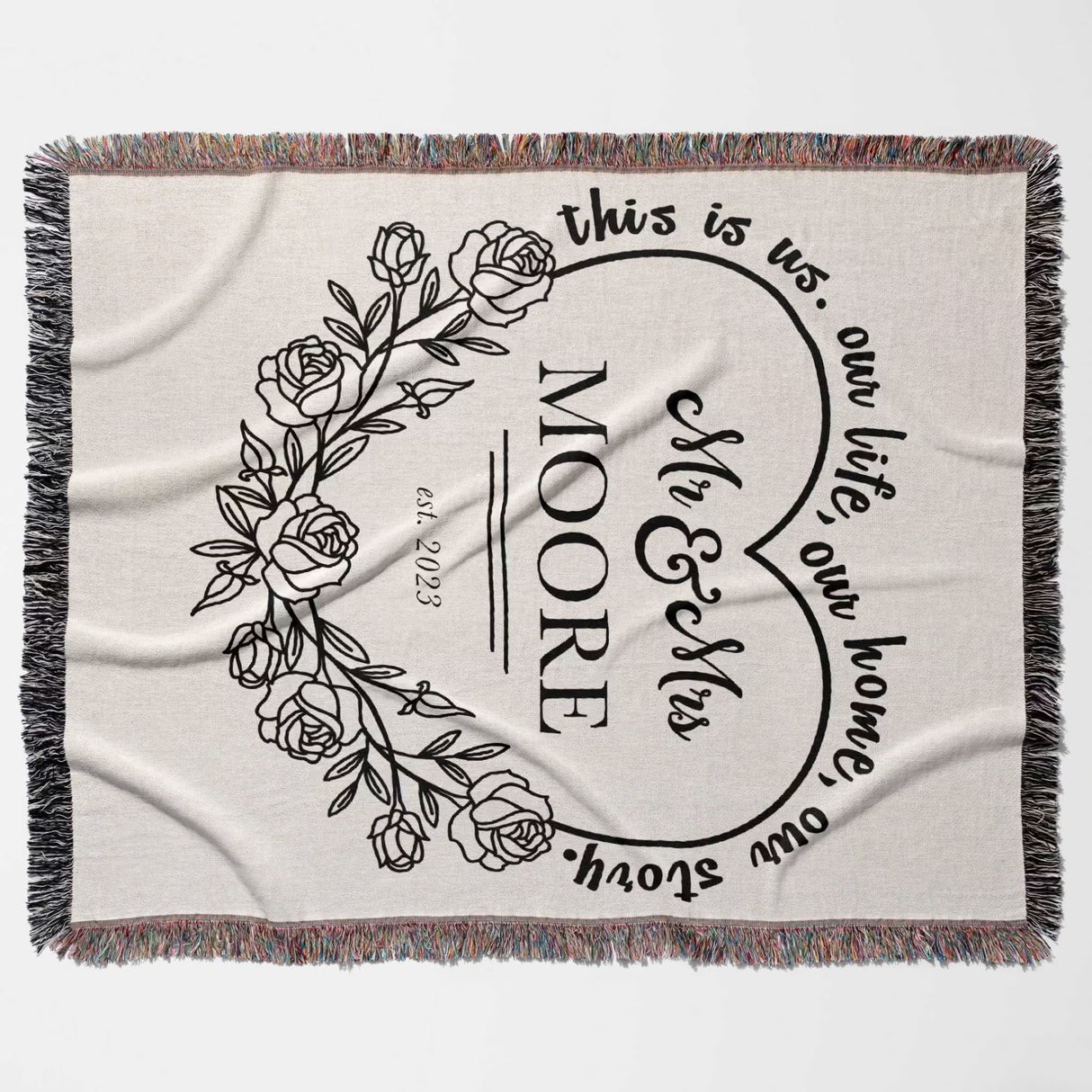Rustic Mr and Mrs 2nd year anniversary gift woven throw blanket with floral design and text 'this is us, our life, our home, our story. MOORE' on a beige background