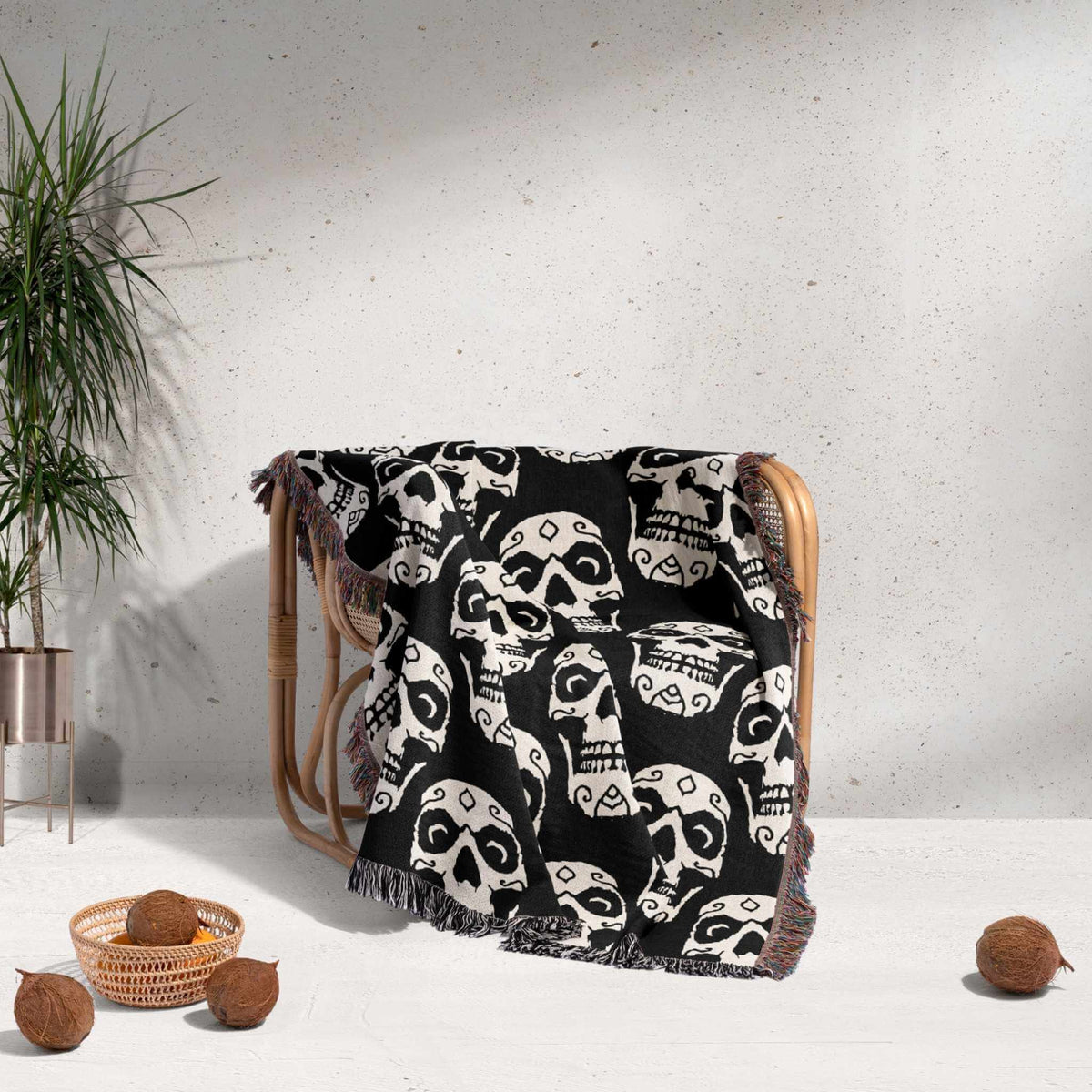 Black and white patterned blanket draped over a chair with a plant and coconuts in the background.