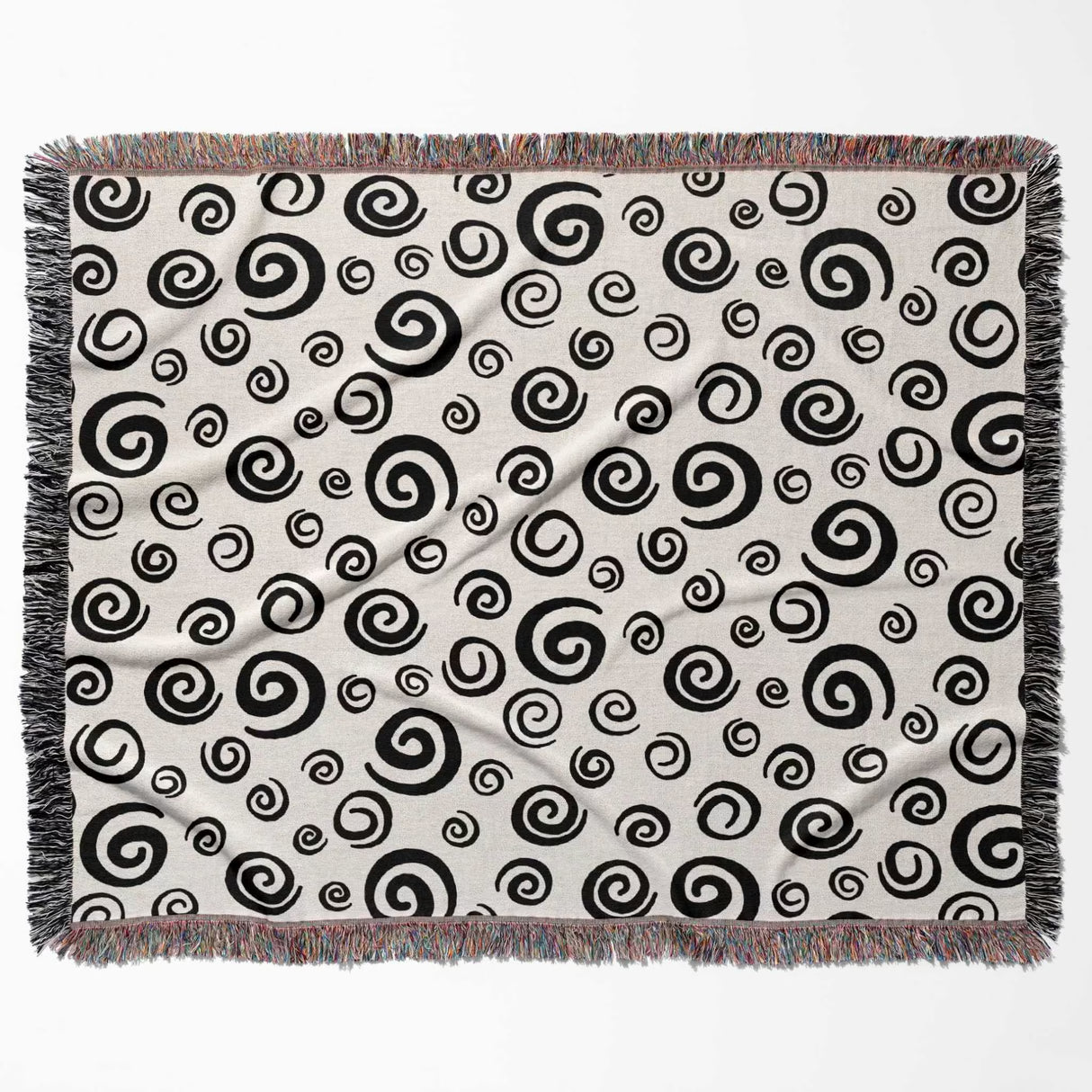 Black and white swirls patterned woven blanket throw with fringe horizontally flat lay on a white background.