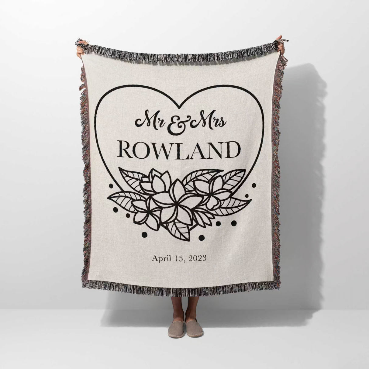 2nd year anniversary gift Mr and Mrs woven throw blanket with 'Mr & Mrs Rowland' design held by a person on a white background