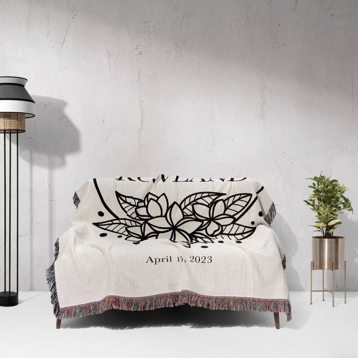 2nd year anniversary gift Mr and Mrs woven throw blanket with black floral design and date on a white couch against a light gray wall.