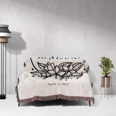 2nd year anniversary gift Mr and Mrs woven throw blanket with black floral design and date on a white couch against a light gray wall.