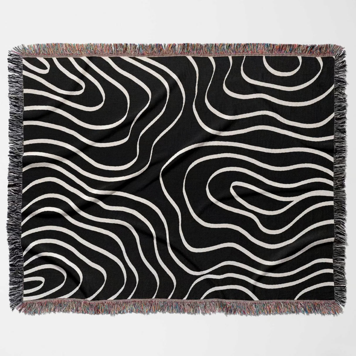 Black and white abstract art waves cotton woven blanket throw tapestry with fringed edges flat lay on a light gray background