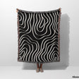 Black and white abstract art waves cotton woven blanket throw tapestry held by a person on a white background