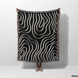 Black and white abstract art waves cotton woven blanket throw tapestry held by a person on a white background