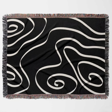 Black and white abstract art waves decorative woven blanket throw flat lay on a light gray background