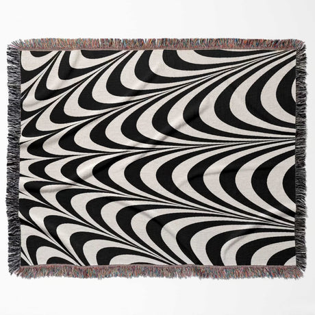 Black and white abstract art wavy woven blanket throw tapestry with fringed edges flat lay on a white background.