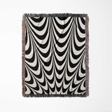 Black and white abstract art wavy woven blanket throw tapestry with fringe full view on a light gray background.
