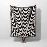 Black and white abstract art wavy woven blanket throw tapestry hold by a person on a white background.