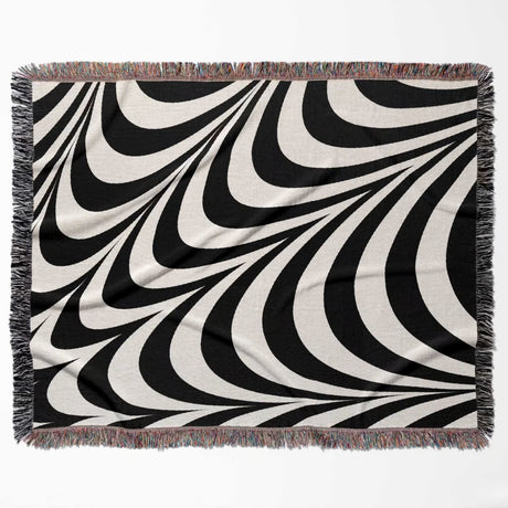 Black and white abstract modern artistic woven blanket throw tapestry with fringes flat lay on a white background.