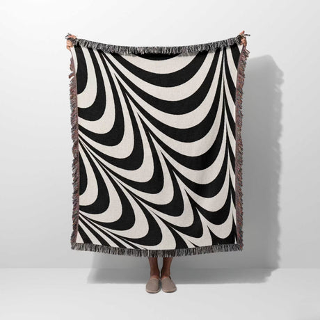 Black and white abstract modern artistic woven blanket throw tapestry held by a person on a white background.
