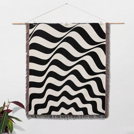 Black and white abstract wavey lines woven blanket throw tapestry hanging on a wall.